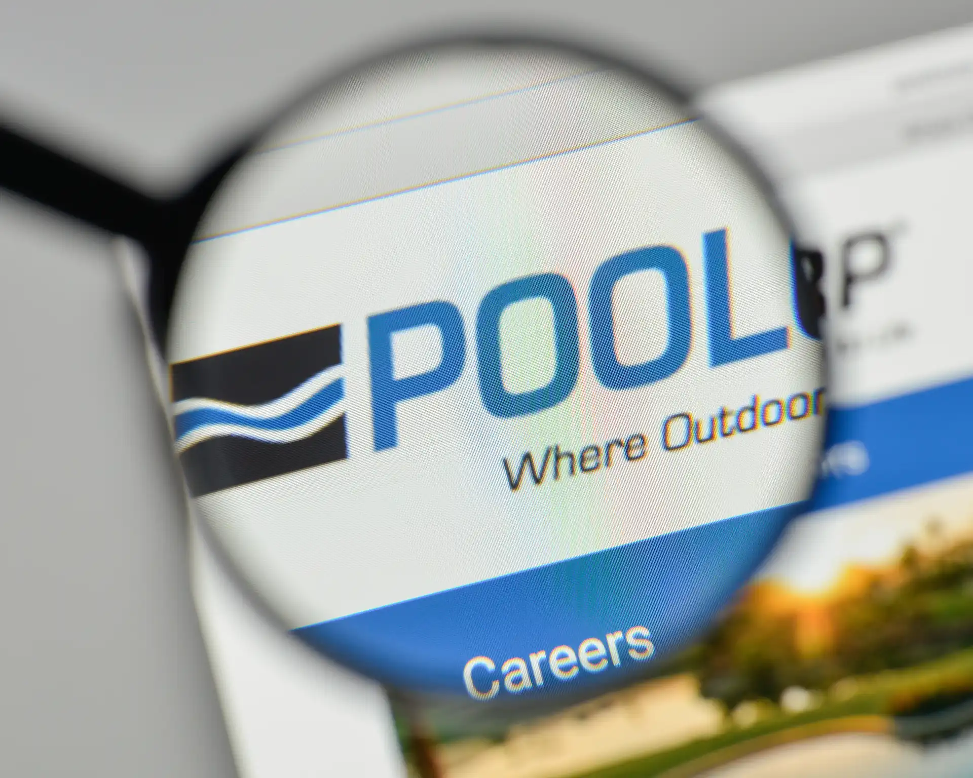 Close-up of a magnifying glass centered on a pool builder business logo displayed on the top left-hand corner of a website.
